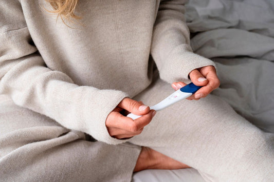 Mains d'une femme tenant un test de grossesse positif