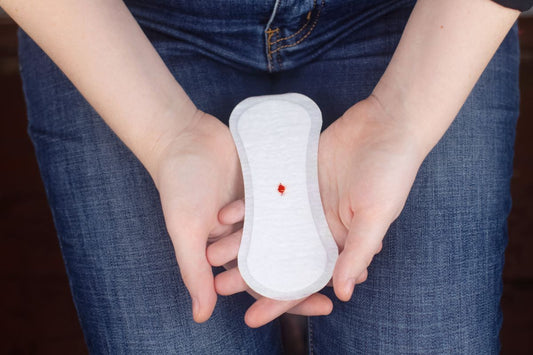 Mains tenant un protège-slip avec une toute petite légère tache de sang