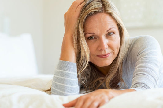 Porträt einer Frau in der Perimenopause, die auf einem Bett liegt.