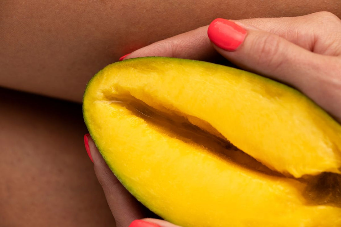 Une main tient un fruit en forme de vulve illustrant un bouton ou irritation intime