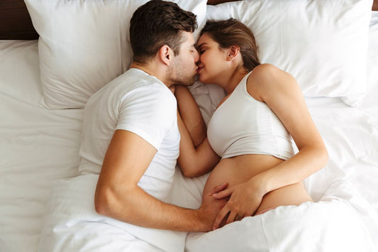 Un couple avec femme enceinte au lit partageant un moment intime