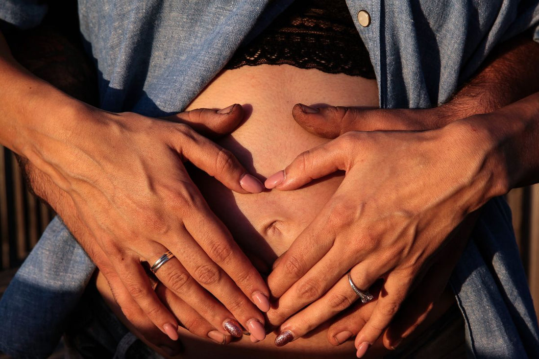 Couple tenant les mains en cœur sur le ventre d'une femme enceinte