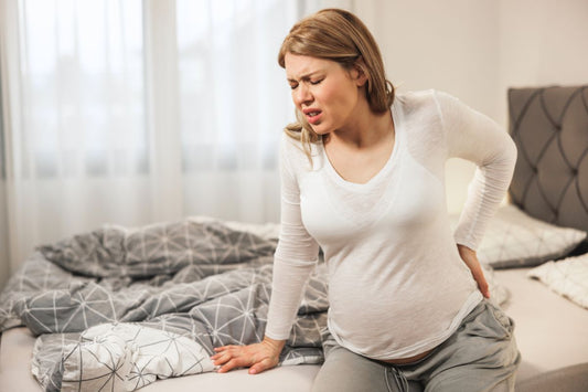 Femme enceinte souffrant de douleur lombaire et pelvienne, assise sur son lit