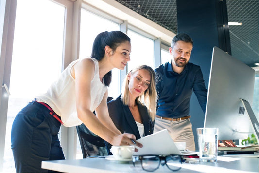 Deux femmes et un homme collaborent au bureau, illustrant gestion réussie des règles au travail