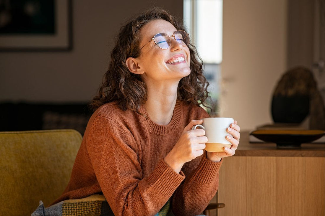Femme souriante avec tasse, routine matinale et calme, essentielle pour la pratique de la symptothermie