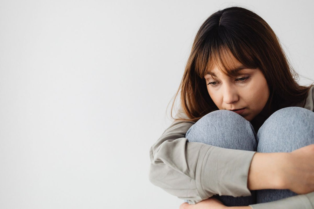 Young woman curled up in a fetal position, expressing emotional stress or psychological distress impacting her cycle