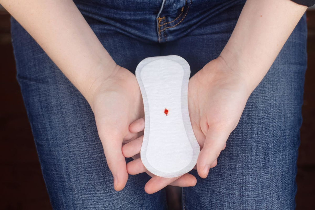Mains tenant un protège-slip avec une toute petite légère tache de sang