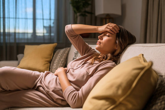 Une femme cherche le repos sur son canapé pour soulager sa migraine cataméniale liés aux règles