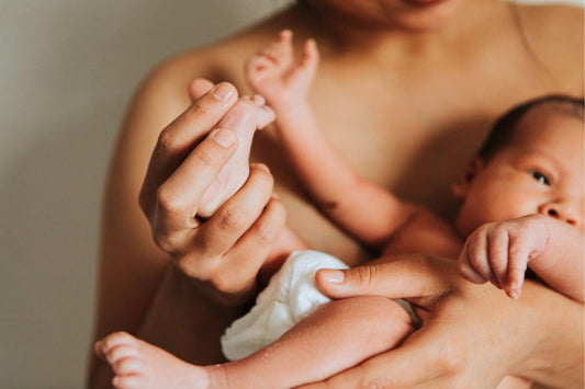 Bebê recém-nascido segurando o dedo da mãe, simbolizando o forte vínculo entre mãe e filho após o parto