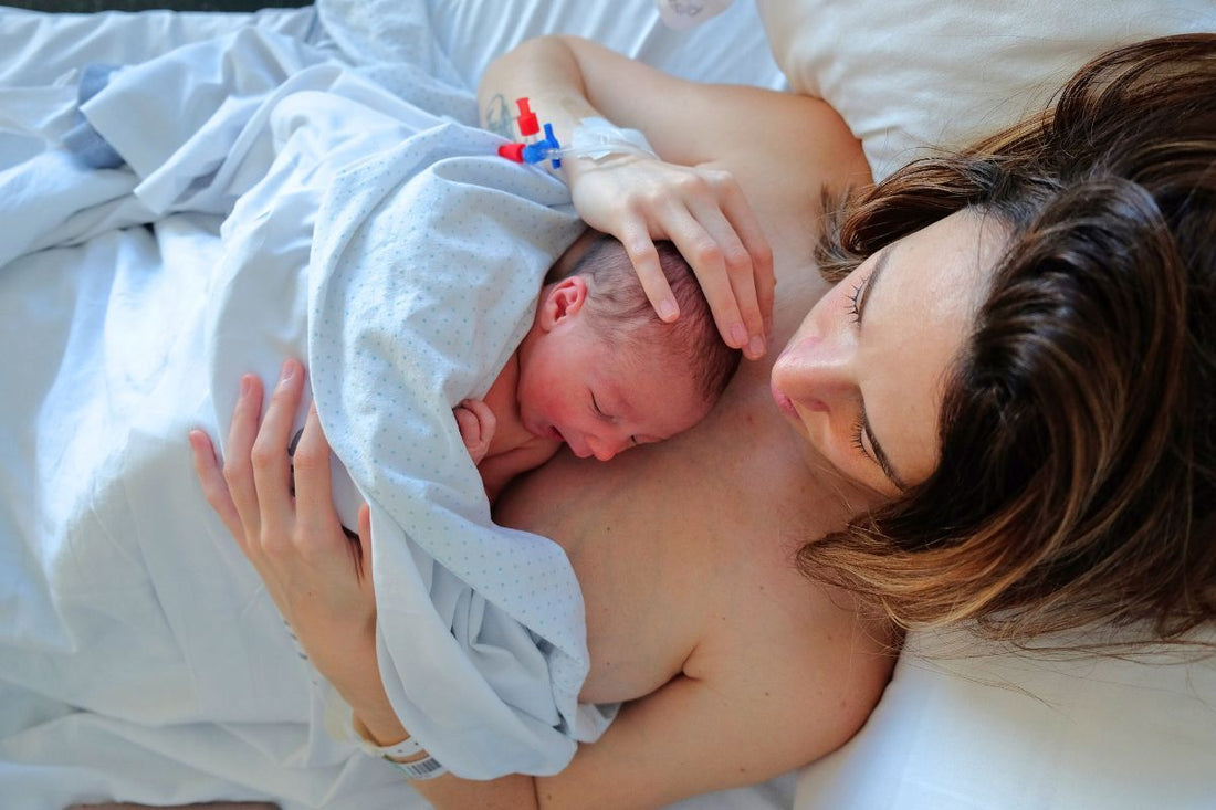 Jeune mère en peau-à-peau avec son nouveau-né, marquant la période post-partum avant le retour des règles