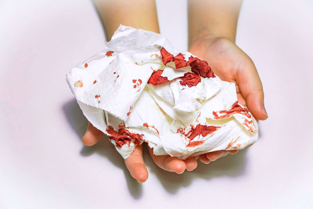 Hands holding blood-stained toilet paper