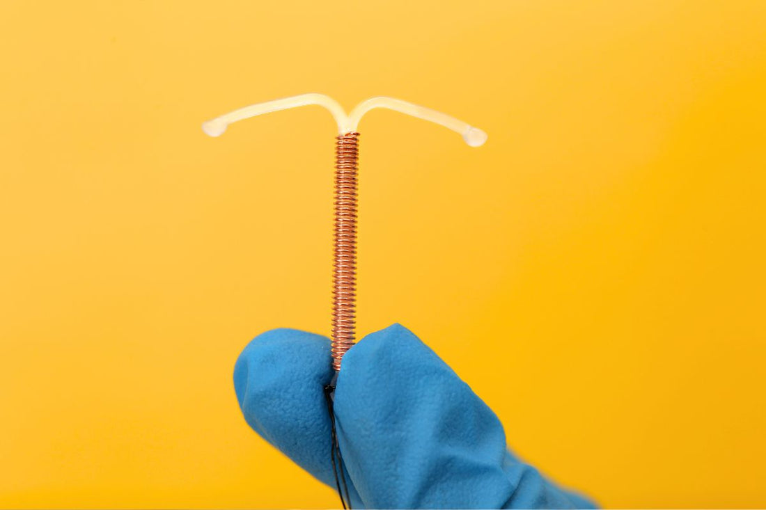 Main gantée tenant un stérilet au cuivre