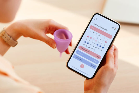 A person holding a smartphone displaying a menstrual cycle tracking app