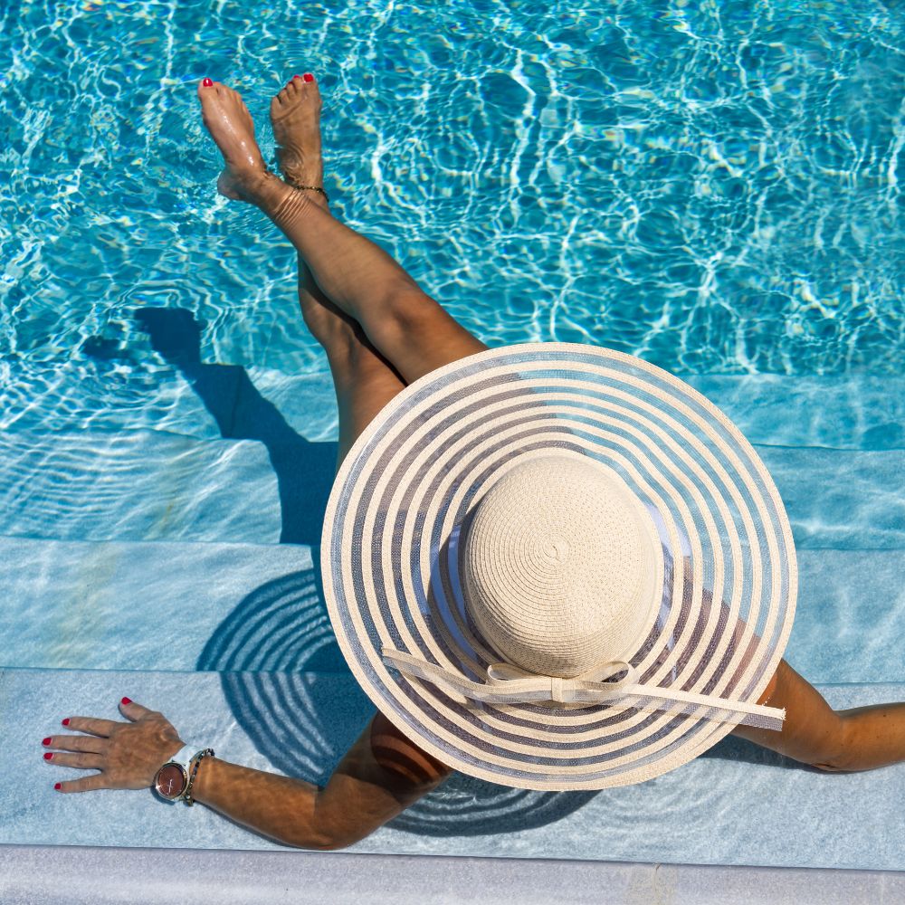 kobieta w menstruacyjnych spodniach od kostiumu kąpielowego w kapeluszu przy basenie